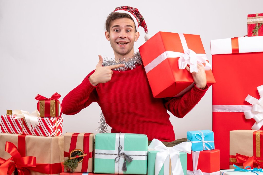 front-view-young-man-pointing-giftbox-sitting-around-xmas-gifts.jpg